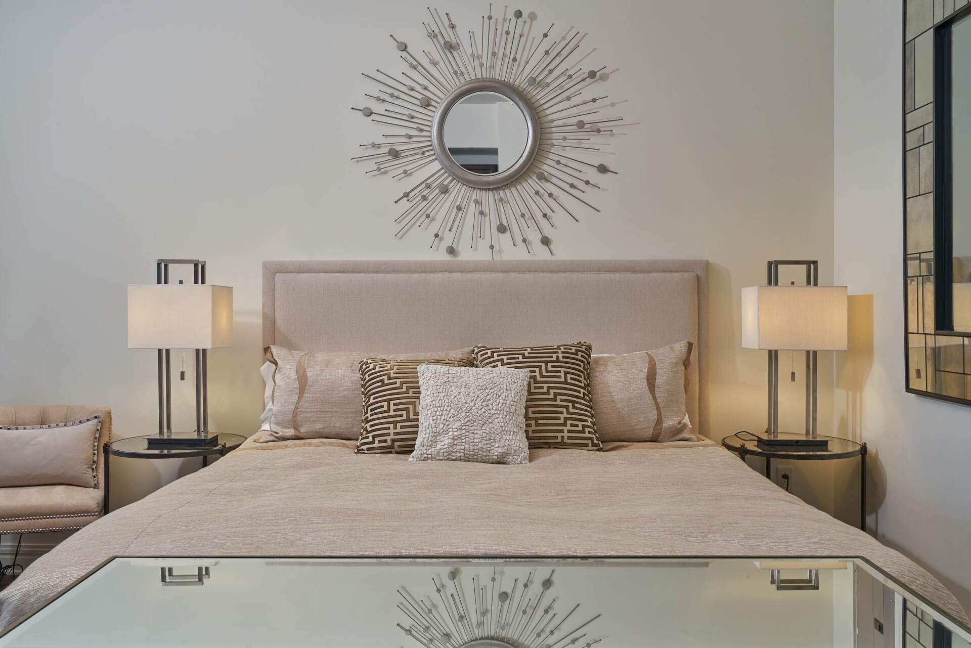 Bedroom with a large bed, decorative mirror above, two lamps on nightstands, and a mirrored bed frame.