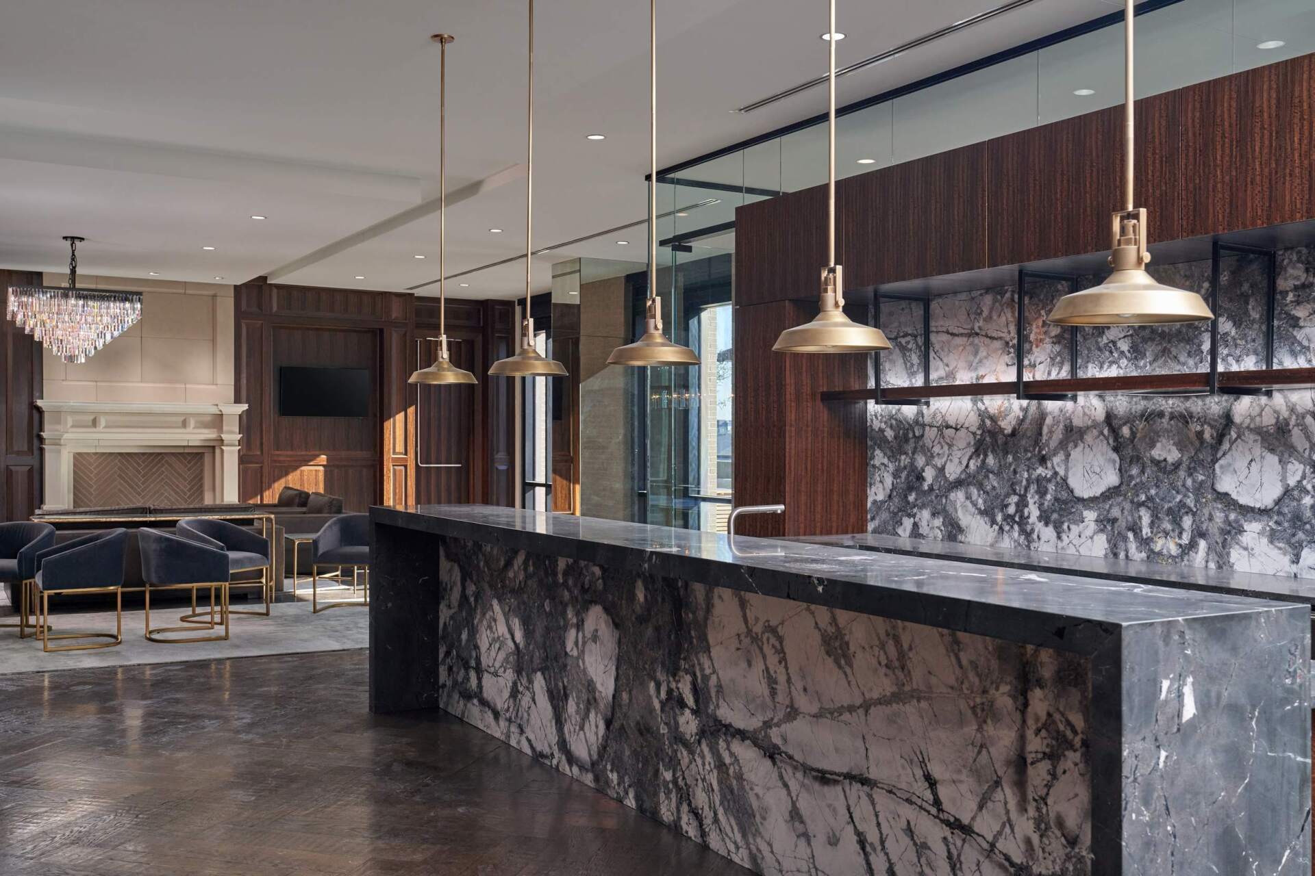 Lounge area with a marble bar and pendant lights; seating area with fireplace in background.