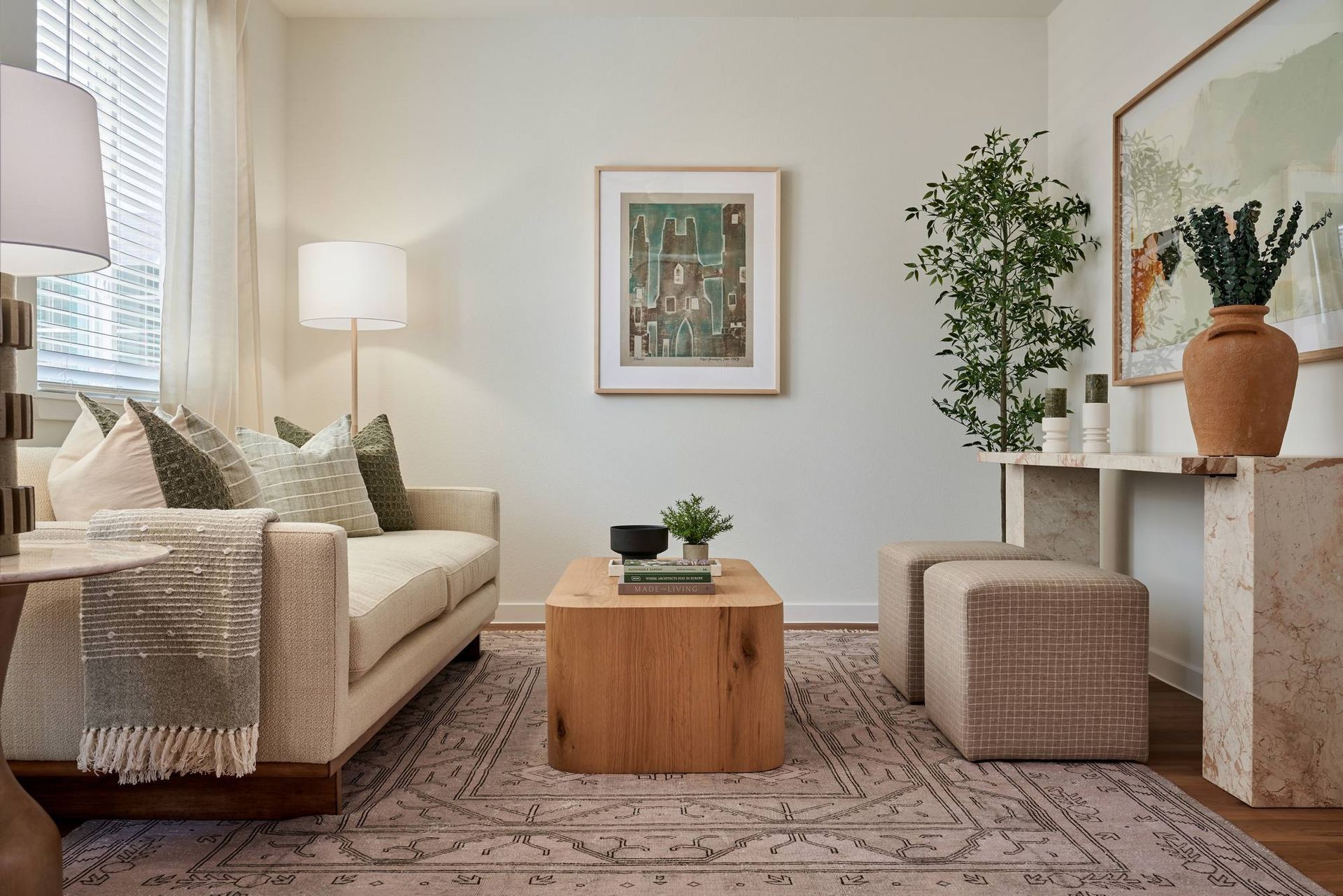 Living room with a beige sofa, wooden coffee table, rug, and artwork.
