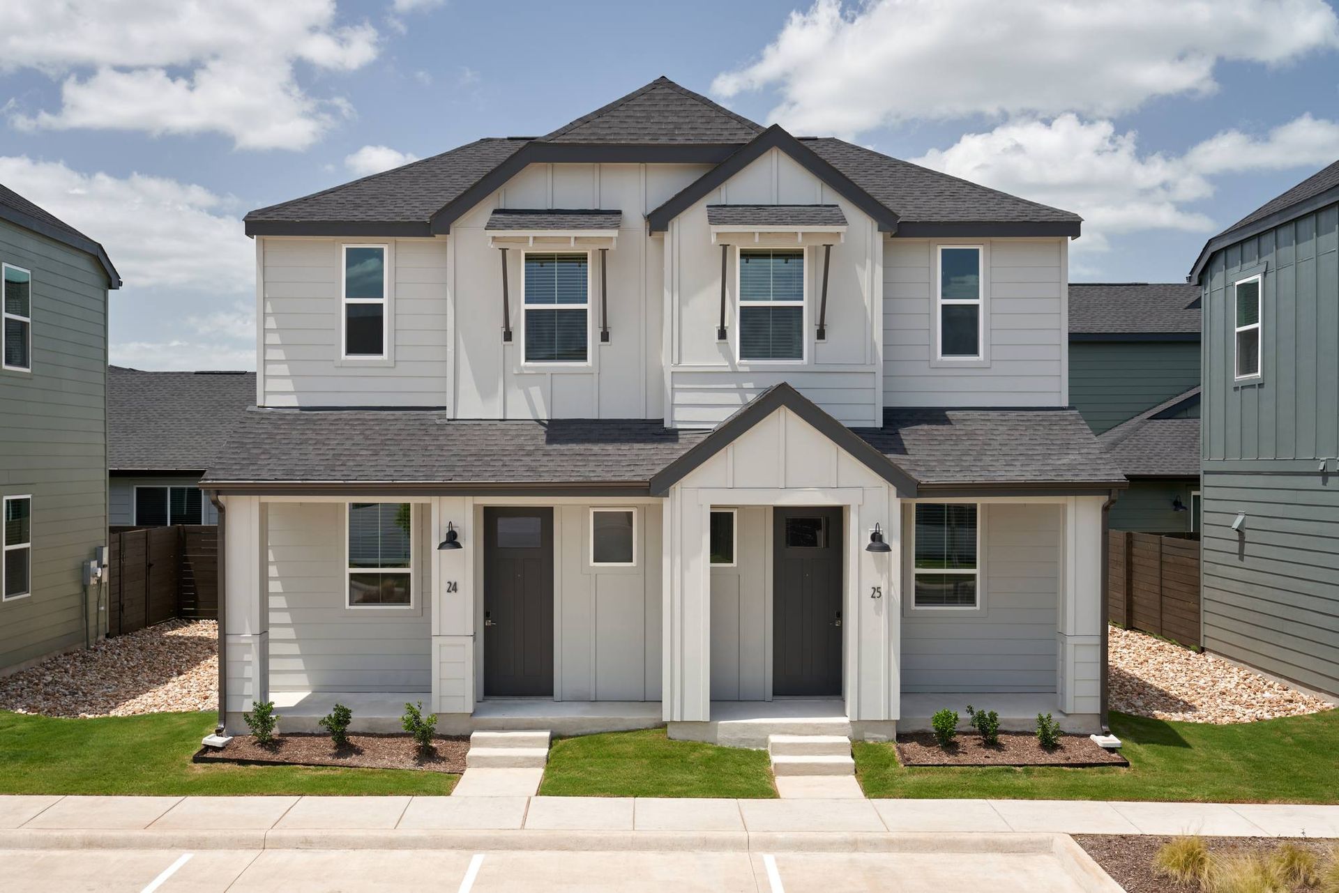 Two-story gray duplex with dark gray roof, two front doors, small front porches, and green lawns.