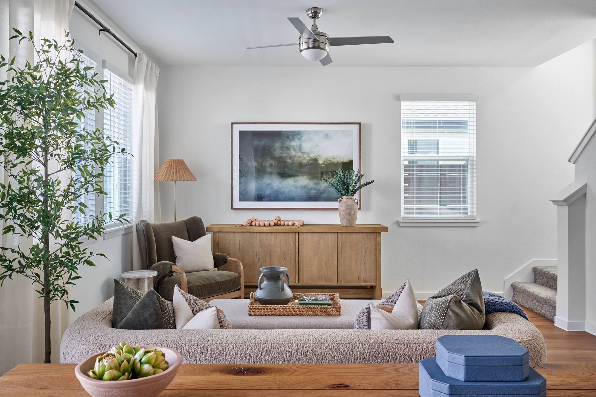 Living room with neutral tones, large sectional, wooden console, and large artwork.
