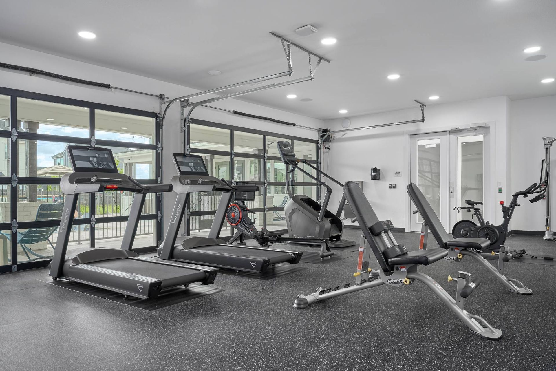 Gym interior with treadmills, weight bench, exercise bike, and glass doors.