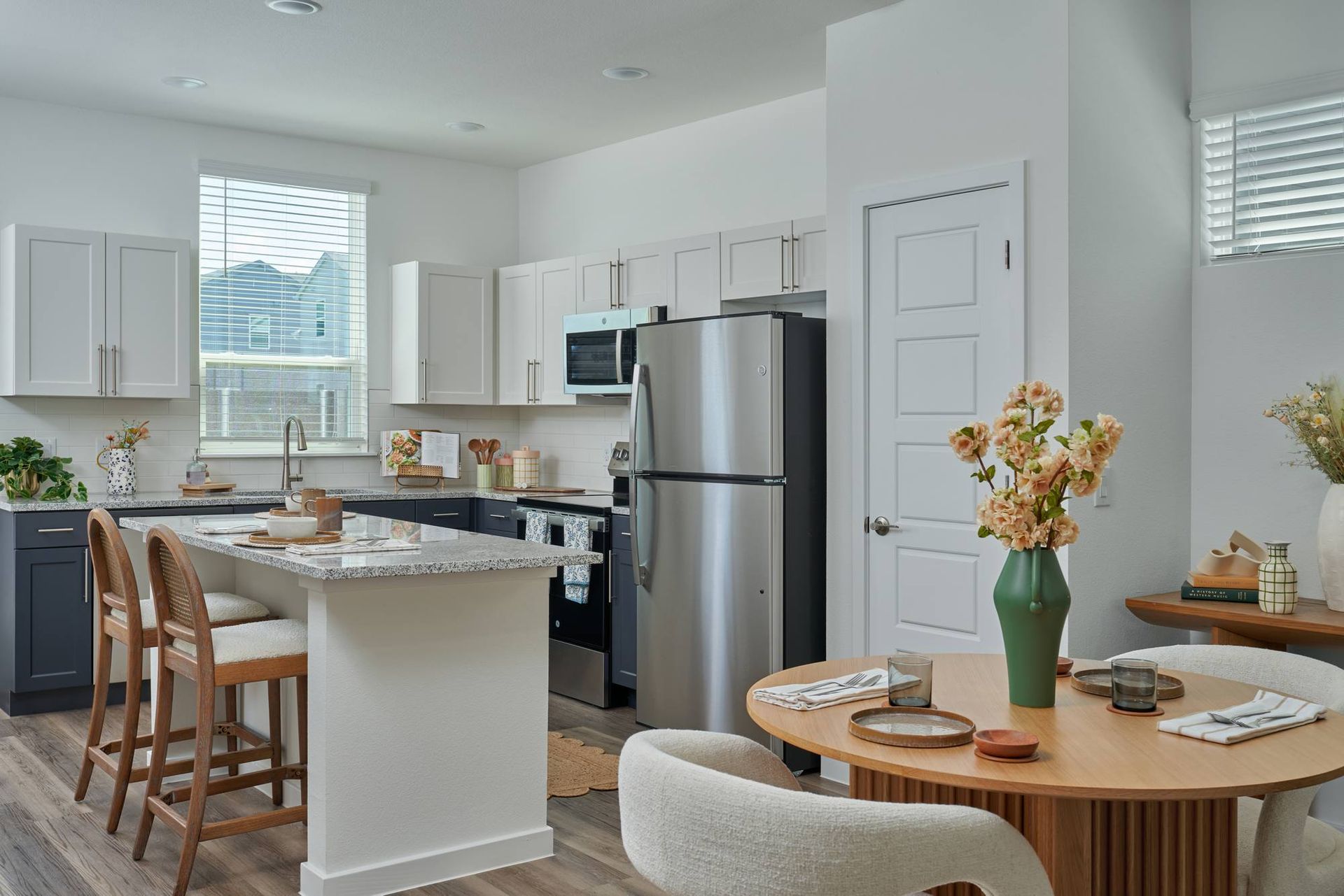 Modern kitchen with light cabinets, stainless steel appliances, breakfast bar, and round dining table.