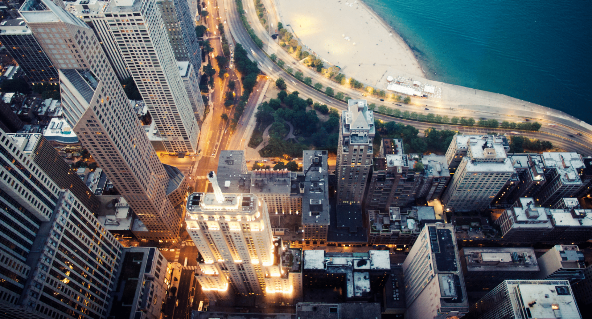 An aerial view of a city at night with a beach in the background.