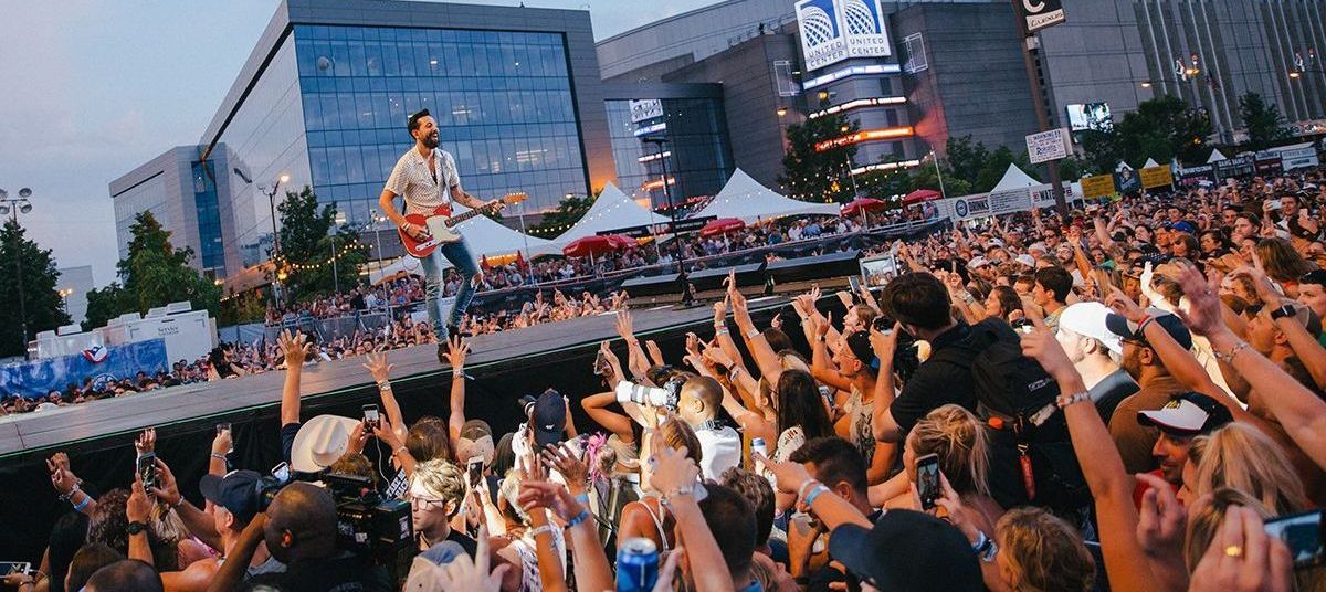 A man is playing a guitar in front of a crowd at a concert.
