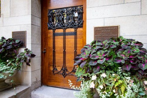 A wooden door is surrounded by flowers and a sign.