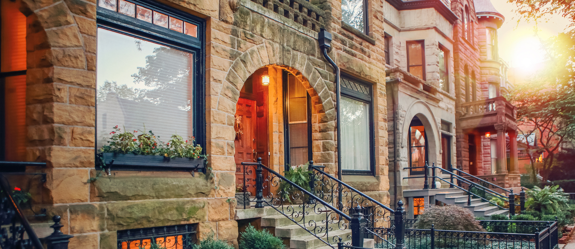 A row of brick houses with stairs leading up to the front door.