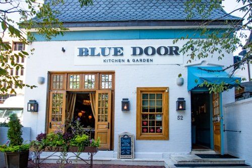 A white building with a blue roof and a sign that says blue door.