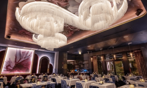 A large dining room with tables and chairs and a large chandelier hanging from the ceiling.