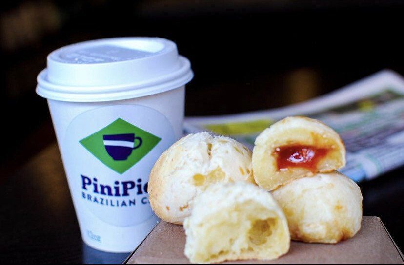 A cup of pinipic brazilian coffee next to some pastries
