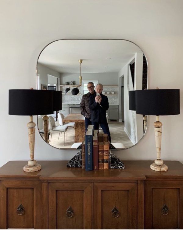 Two men are taking a picture of themselves in a mirror