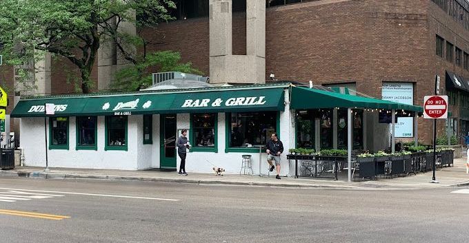 A restaurant with a green awning is on the corner of a city street.