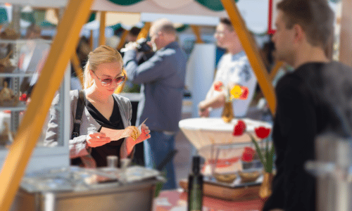 A woman is eating a hot dog at a market.