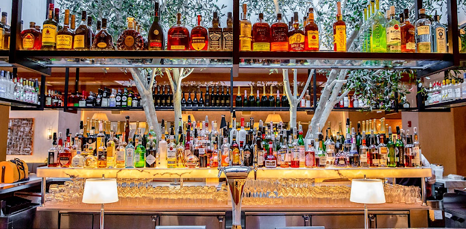A bar filled with lots of bottles of liquor and glasses.