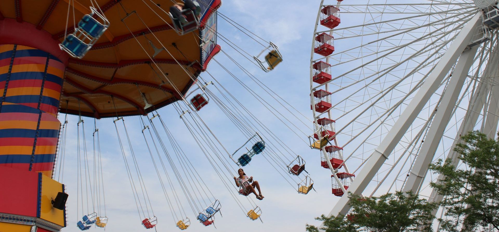 A group of people are riding a swing ride next to a ferris wheel.