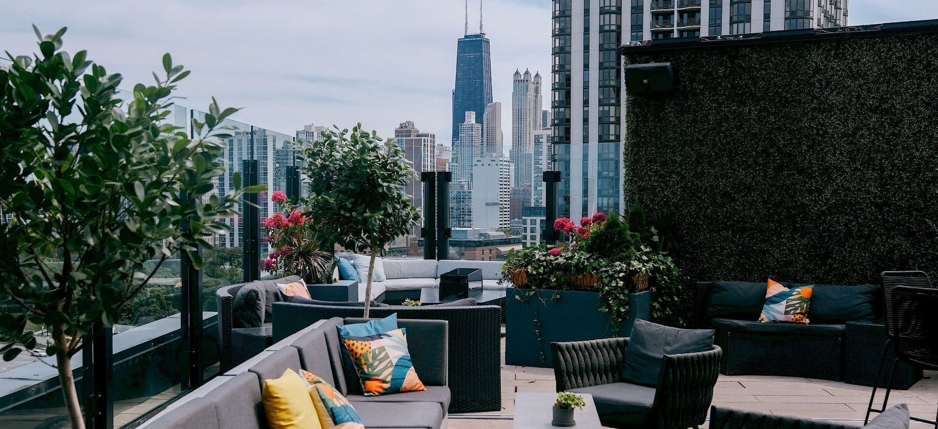 A rooftop patio with a view of the city and a couch and chairs.