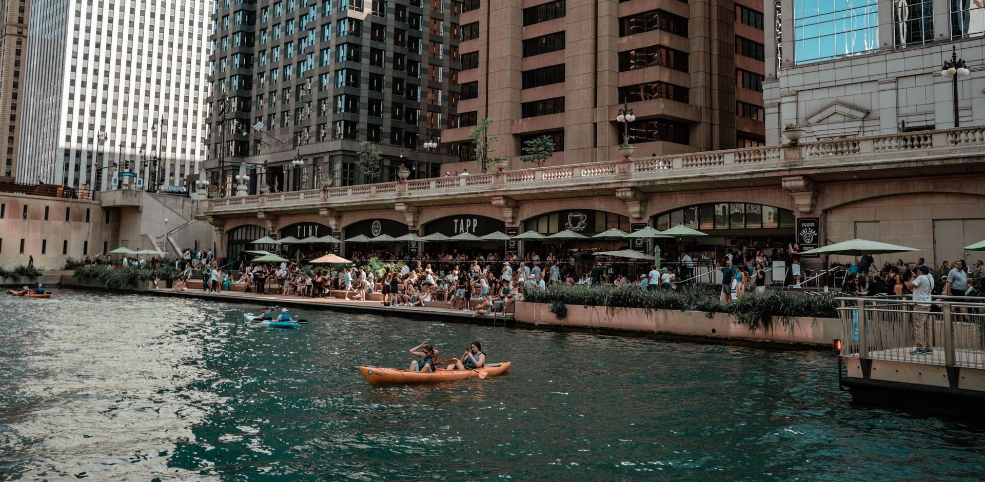 A group of people are rowing a kayak down a river in a city.
