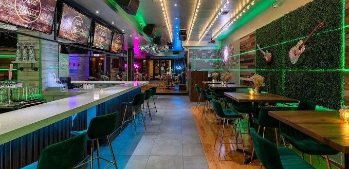 A restaurant with tables and chairs and a long bar.
