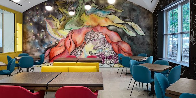 A dining room with tables and chairs and a mural on the wall.