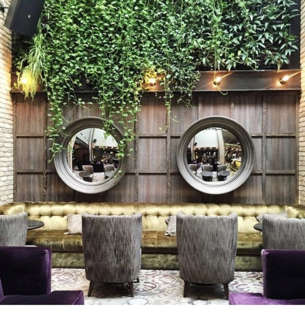 A living room with a couch and chairs and two mirrors on the wall