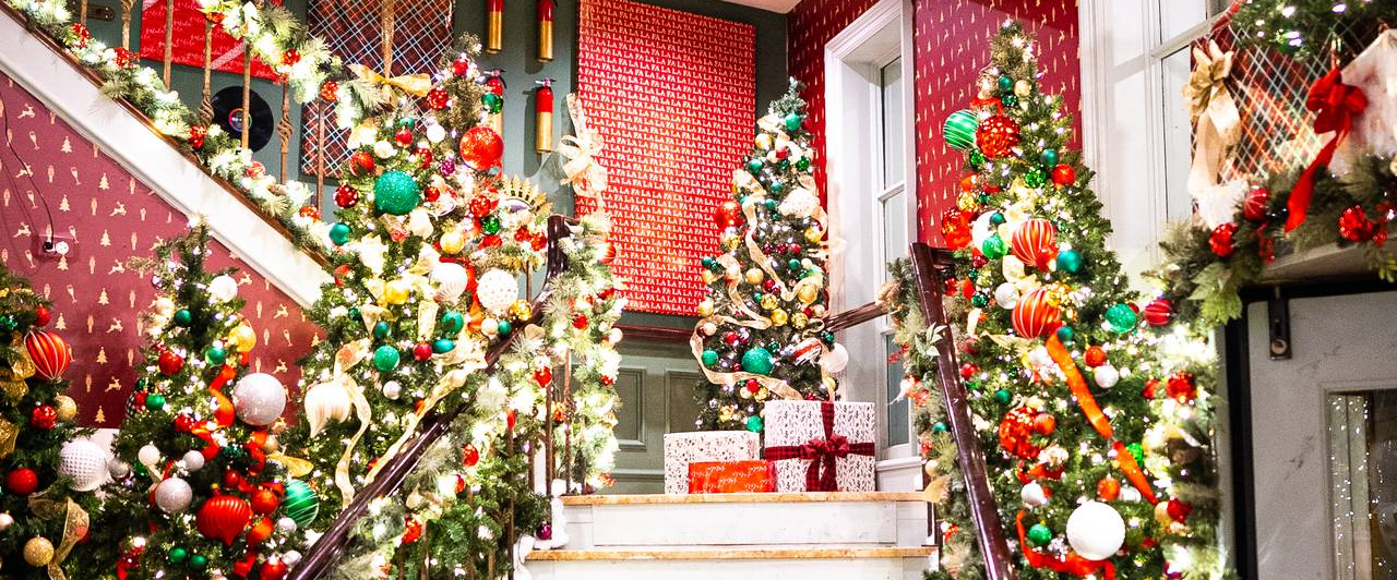 A hallway filled with christmas trees and presents.