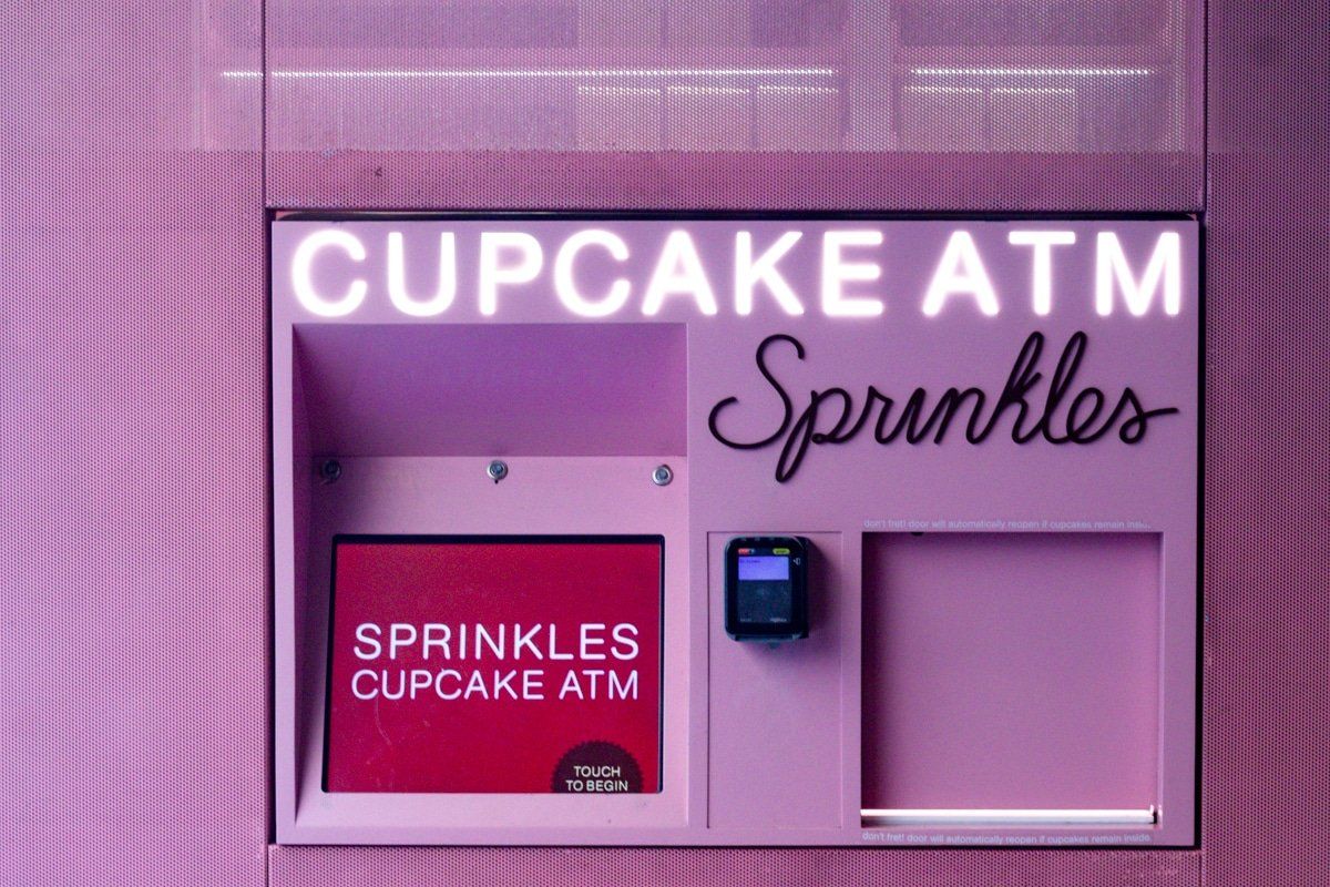 A pink cupcake atm with sprinkles on it
