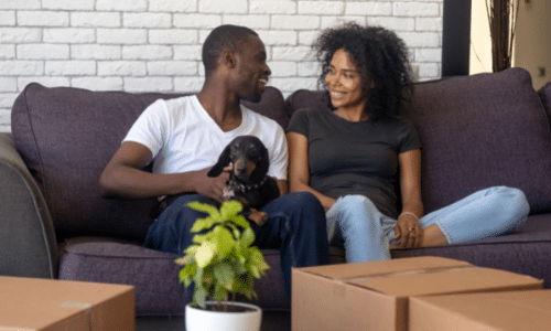 A man and a woman are sitting on a couch with a dog.