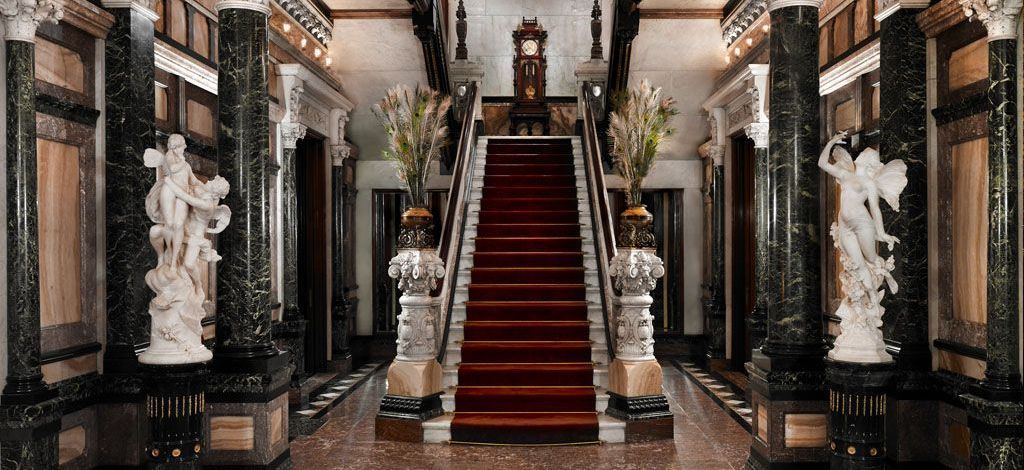 A staircase with a red carpet and statues in a building