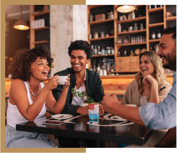 A group of people are sitting at a table in a restaurant drinking coffee.