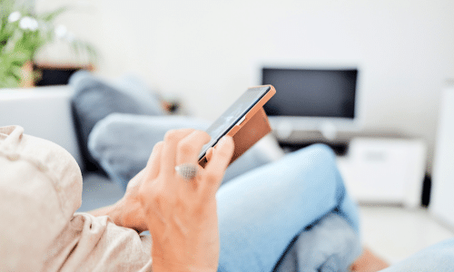 A person is sitting on a couch using a cell phone.