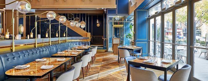 A restaurant with tables and chairs and a lot of windows.