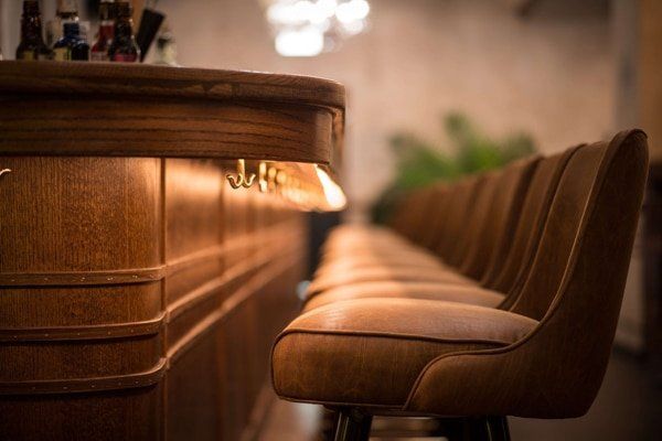 A row of chairs sitting next to a wooden bar in a restaurant.
