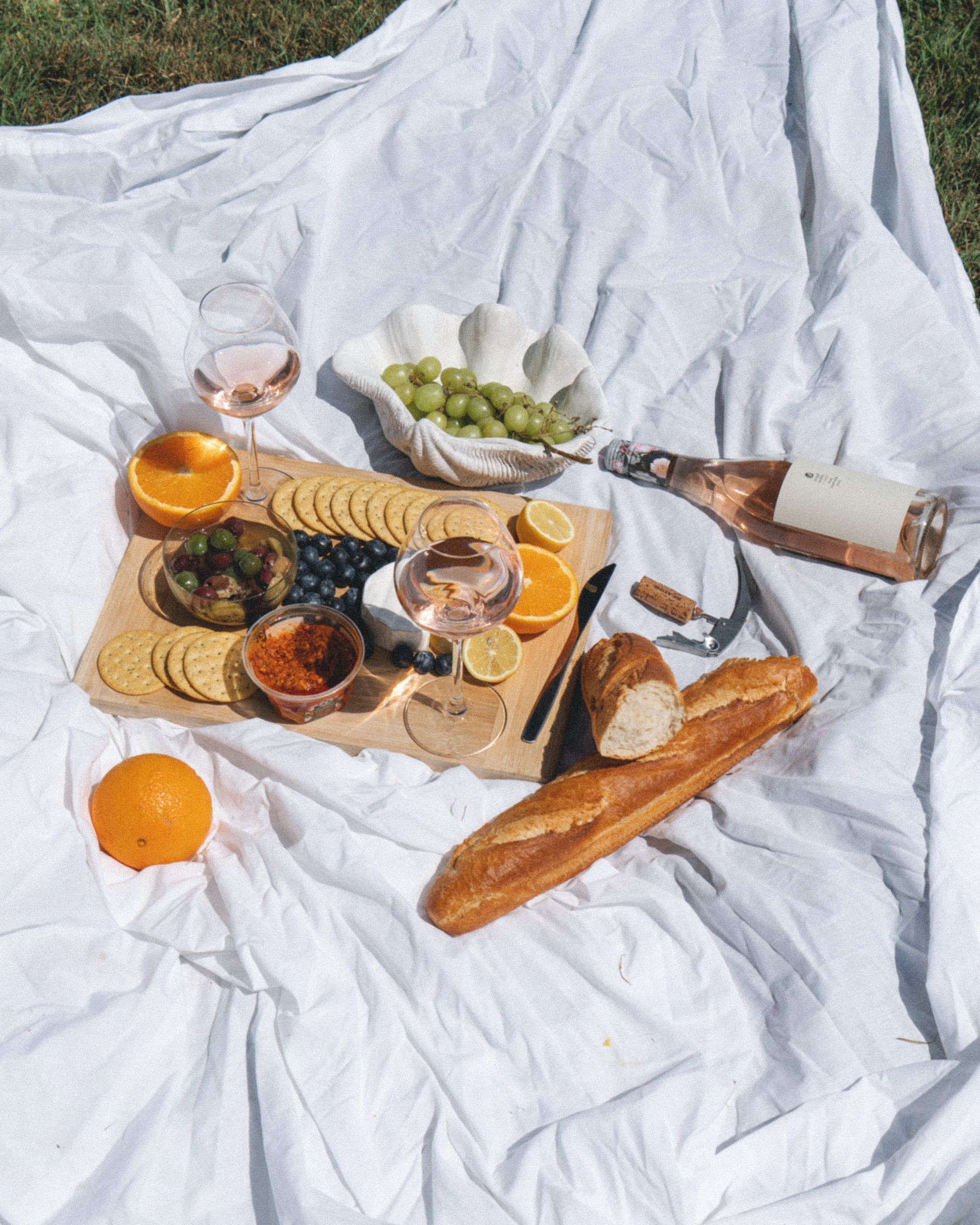 A picnic blanket with food and wine on it.