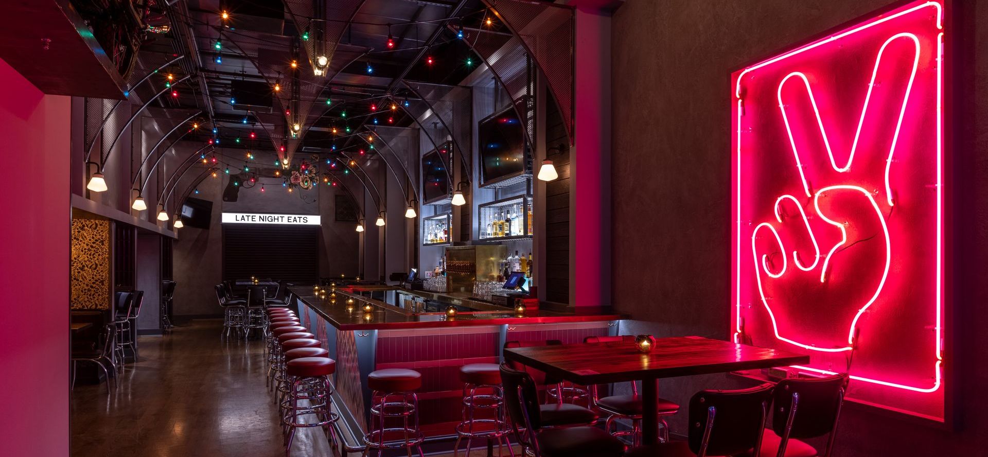 A neon sign with a peace sign on it in a bar.