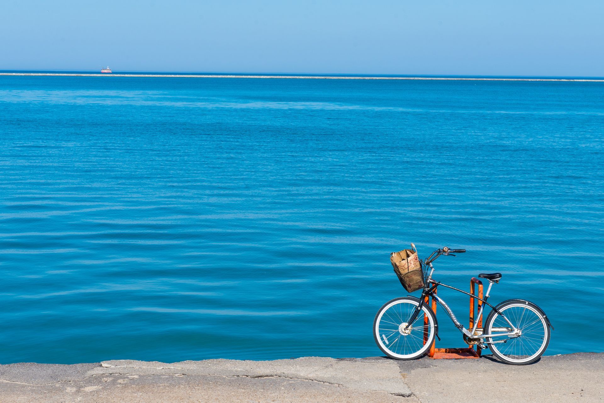 A bicycle is parked on the shore of the ocean.