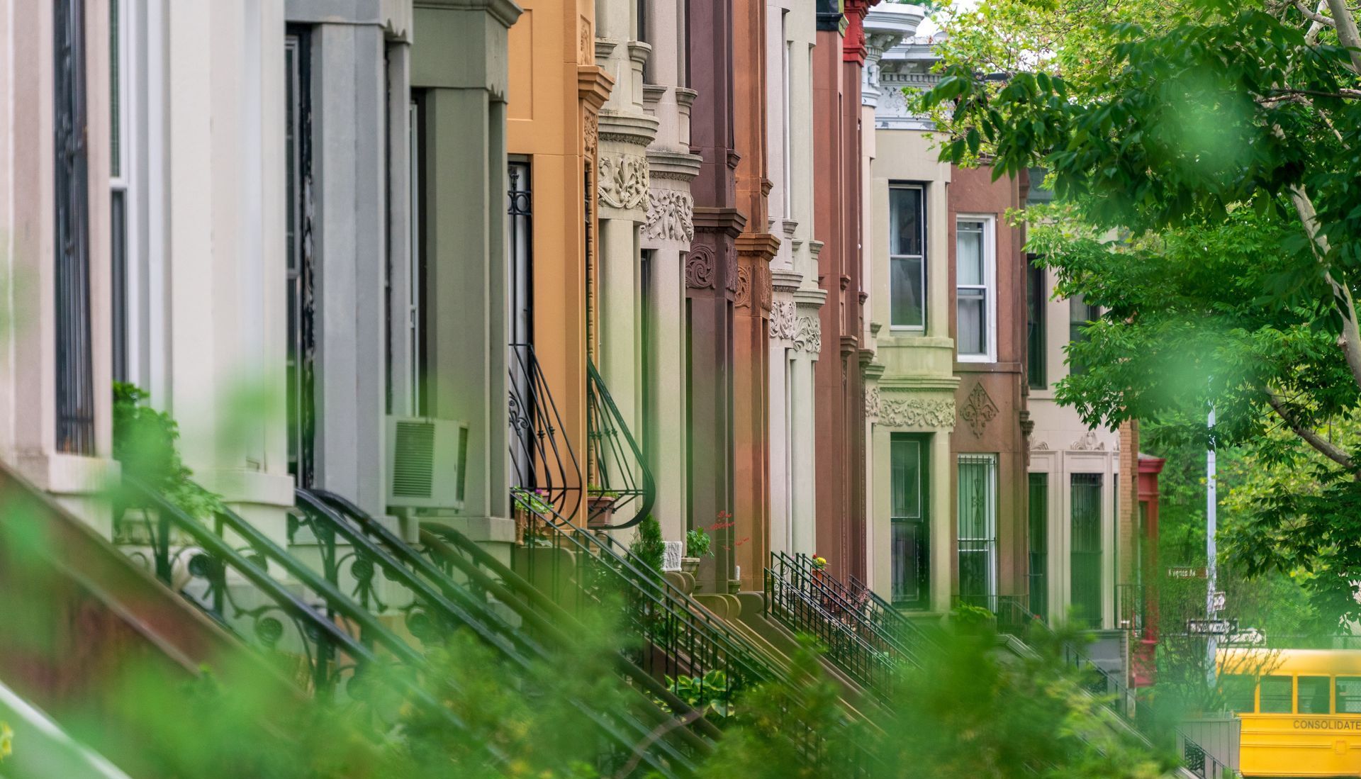 A yellow school bus is parked in front of a row of houses.