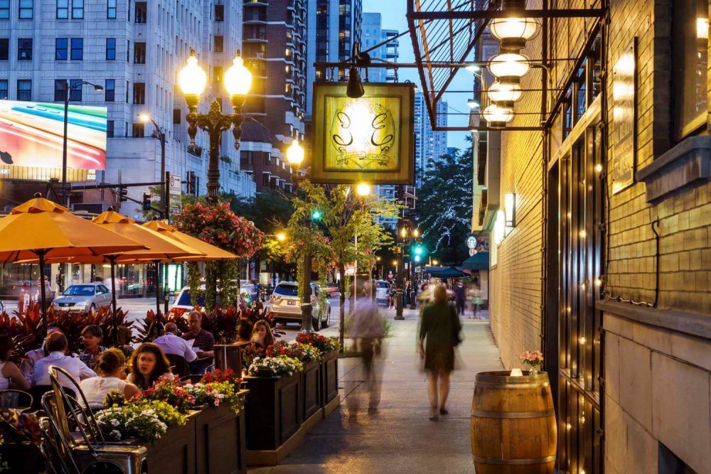 A group of people are walking down a sidewalk in a city at night.