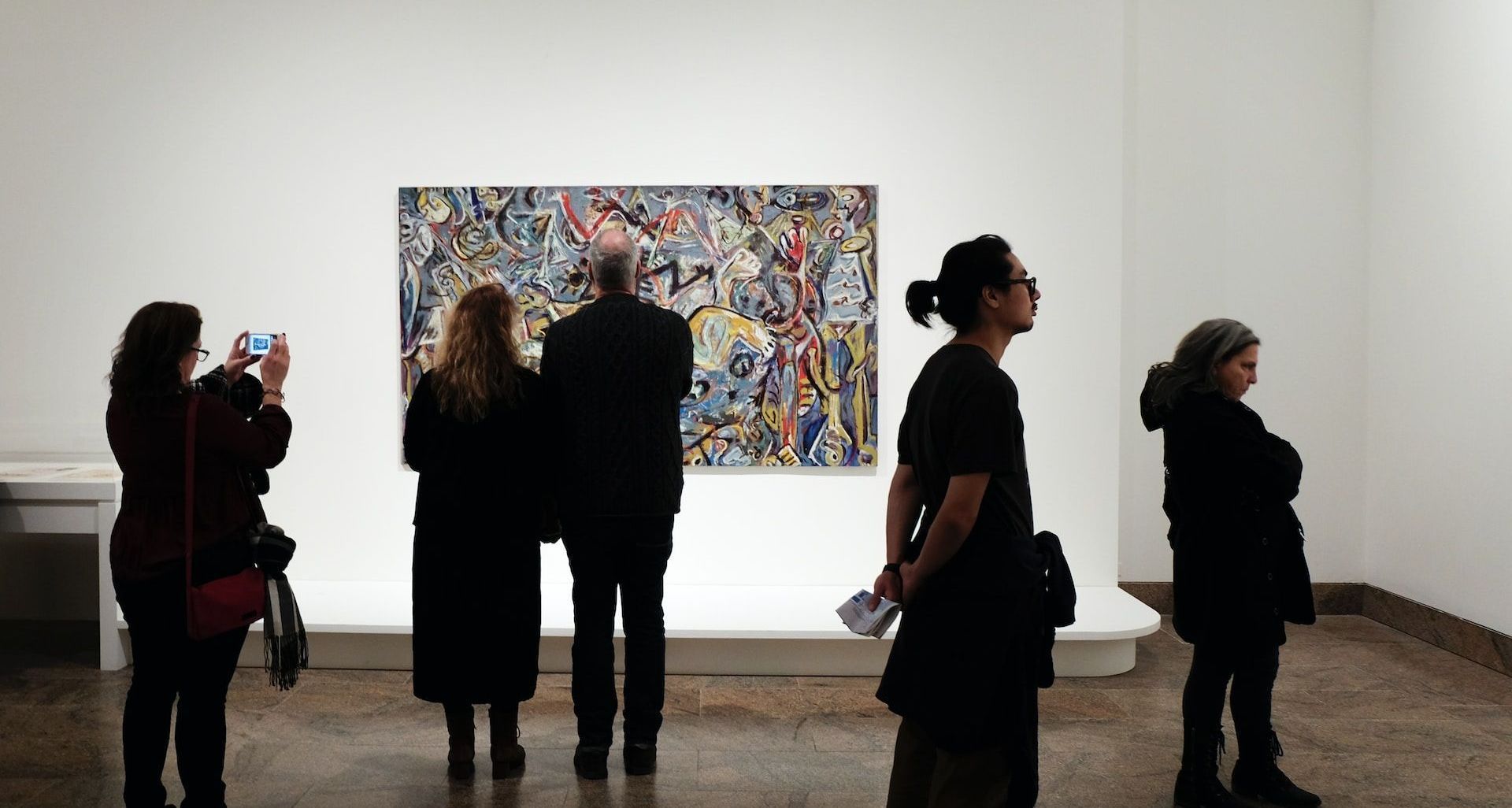 A group of people are looking at a painting in a museum.