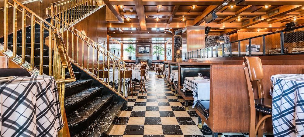 A restaurant with tables and chairs and a checkered floor.