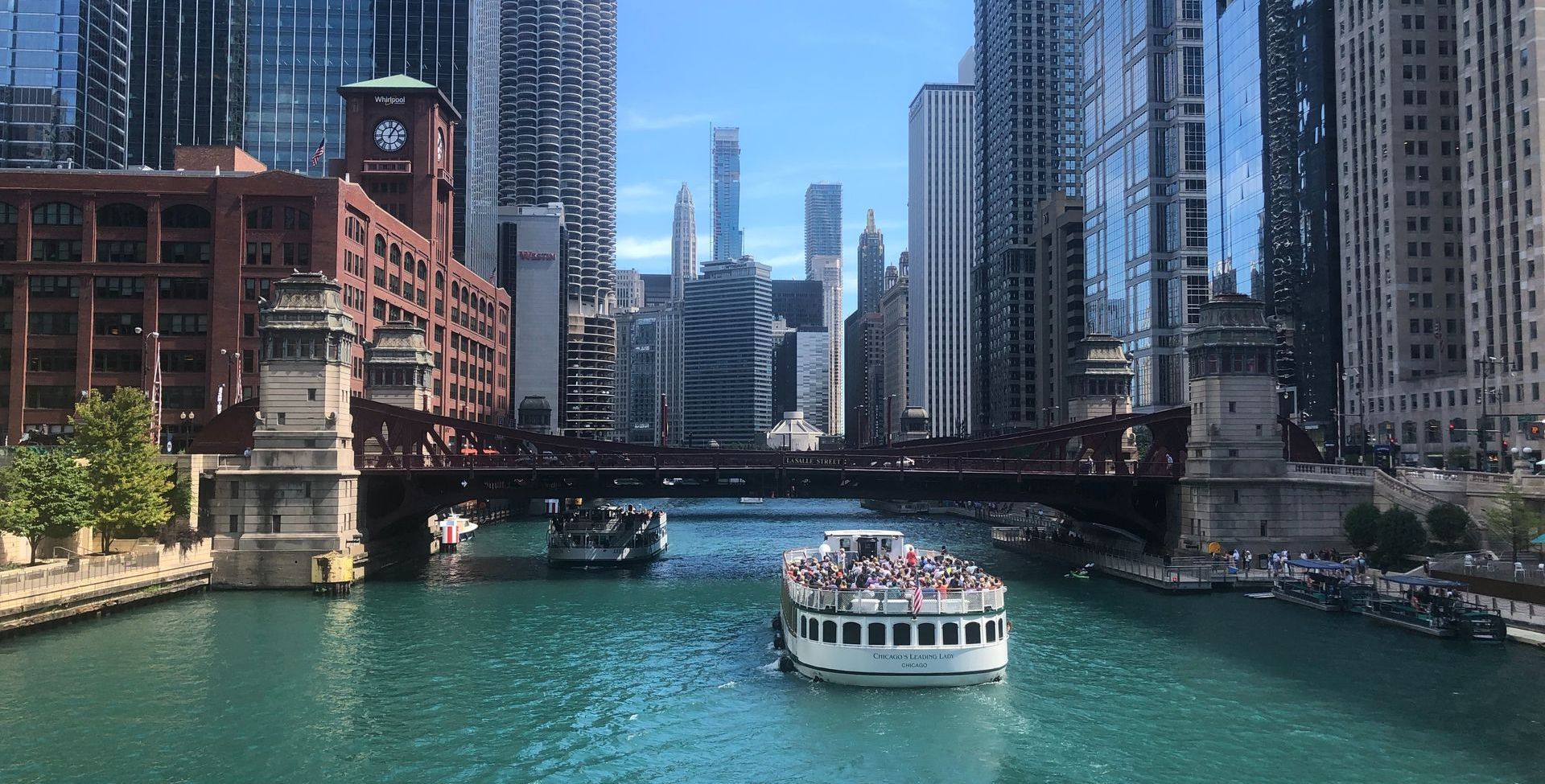 A boat is floating down a river in a city.