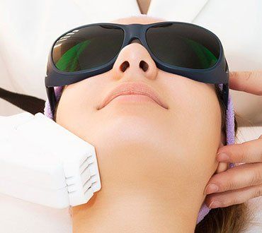 Mujer recibiendo tratamiento láser facial con protección ocular