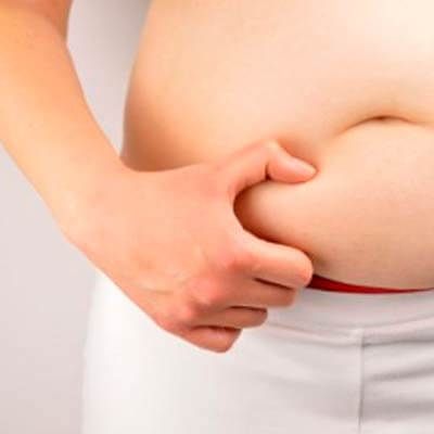 Mano sujetando grasa localizada en abdomen