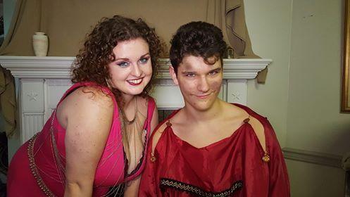 A man and a woman are posing for a picture in front of a fireplace, representing Ares.