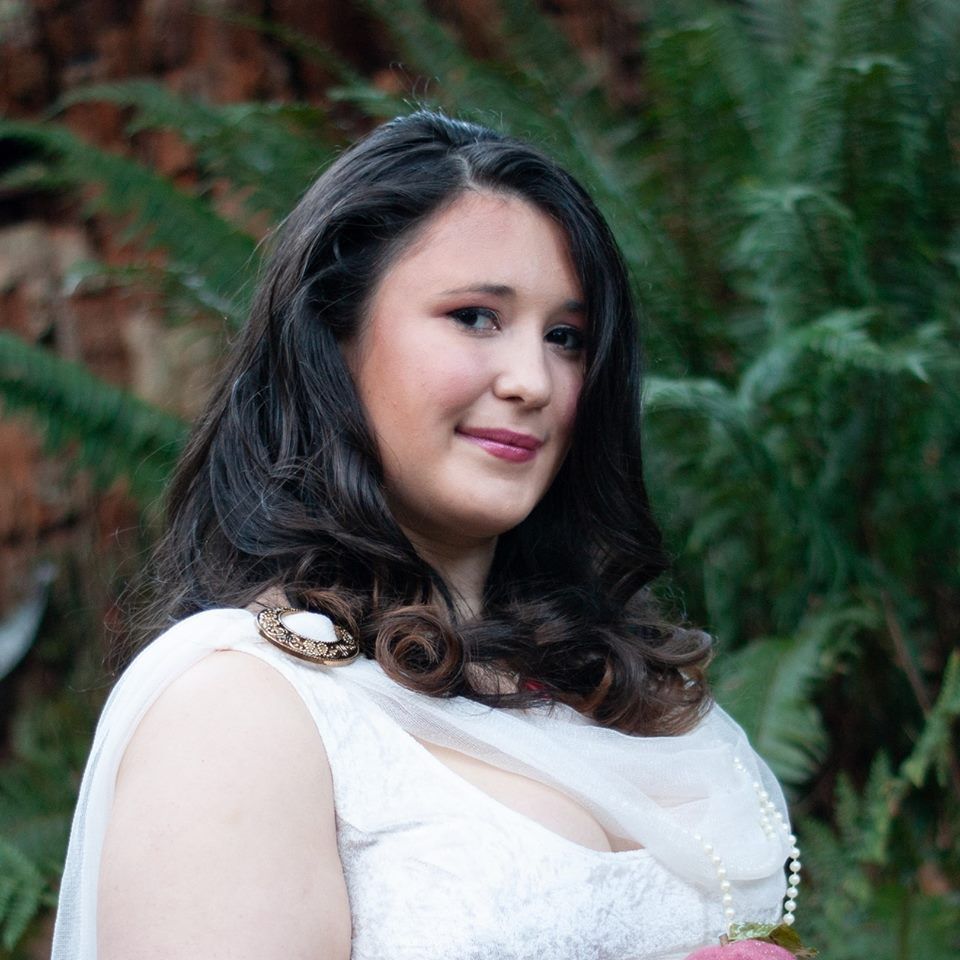 A woman in a white dress is holding a bouquet representing Persephone.