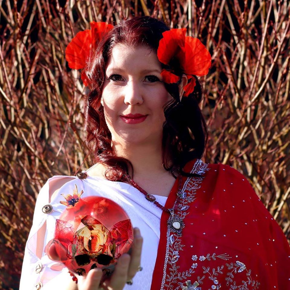 A woman with red flowers in her hair is holding a pomegranate, representing Persephone.