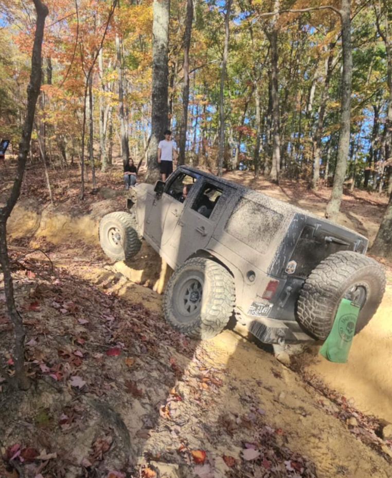 Black Jeep on rocky trail overlooking autumn hills under a cloudy sky