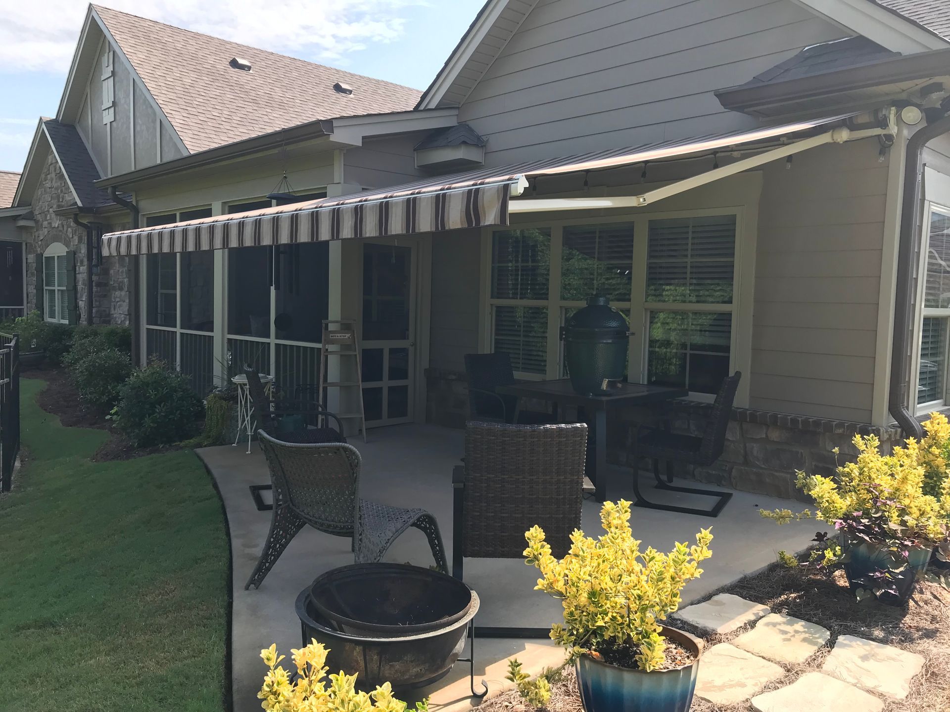Patio with retractable awning, seating, and screen enclosure attached to a house.