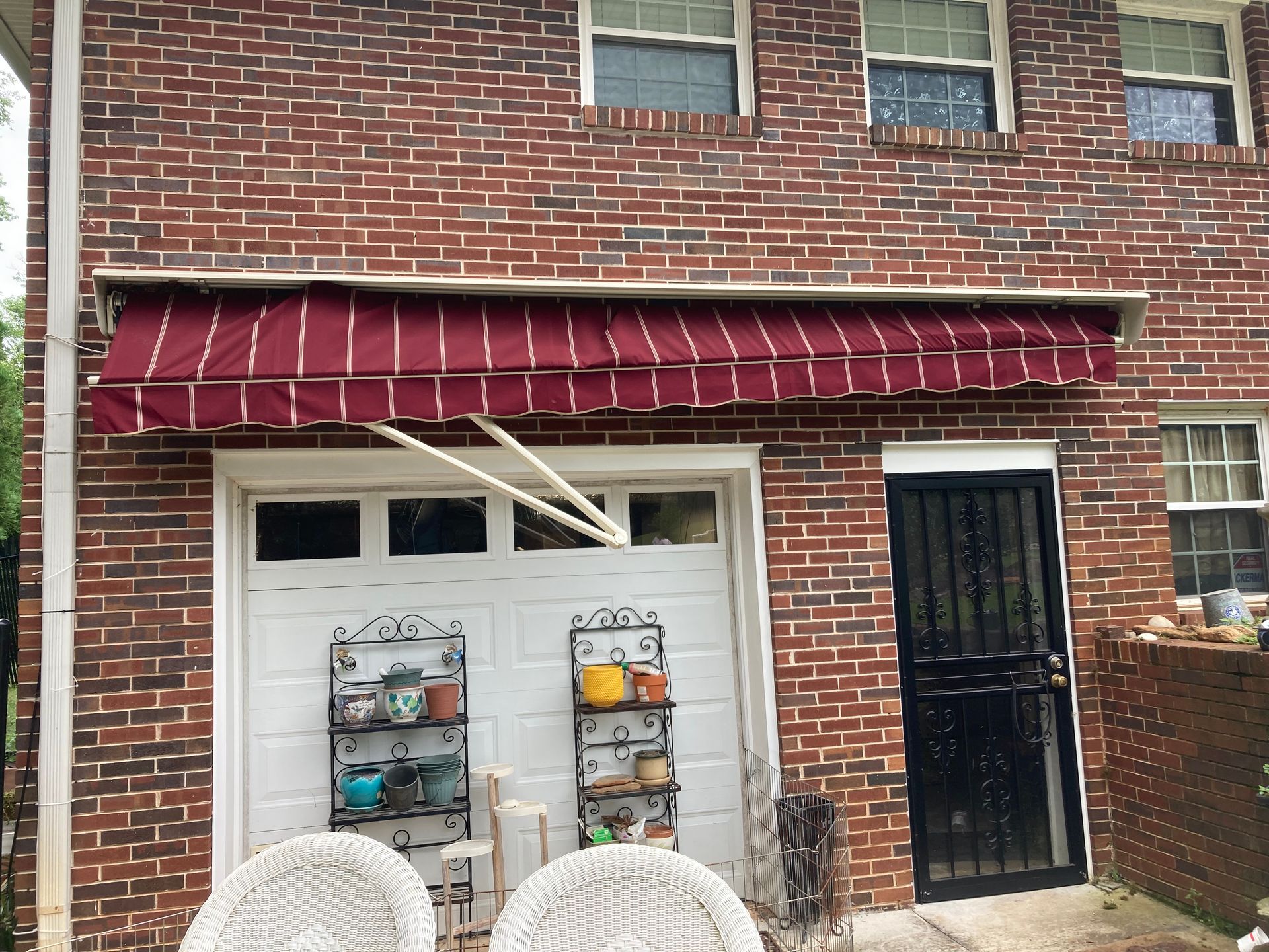 Red and white striped awning over a white garage door, set against a red brick building.