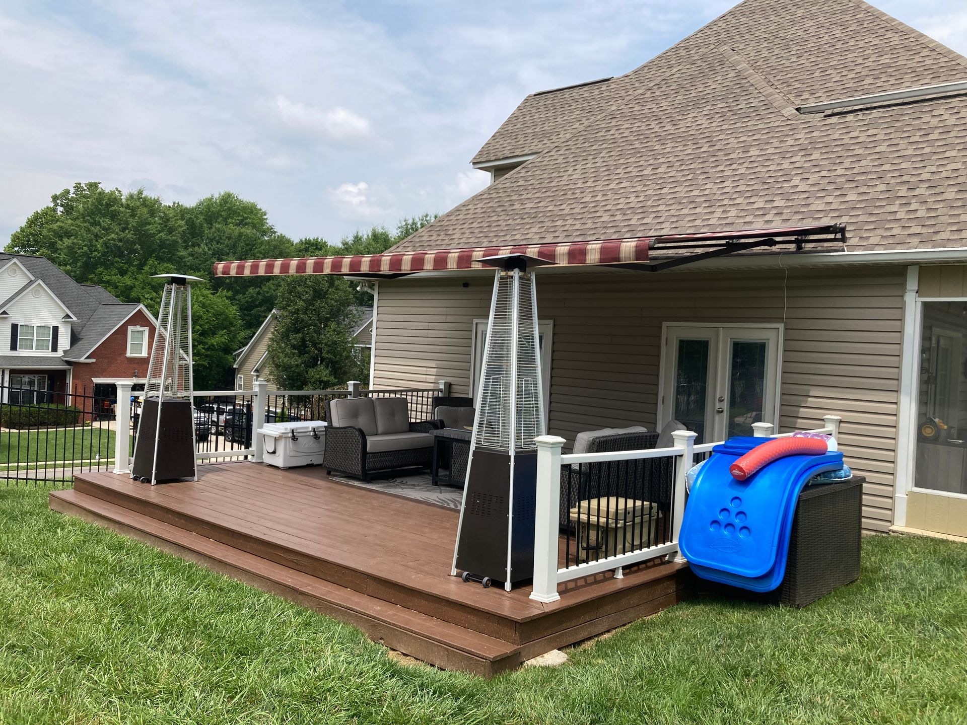 A deck with patio furniture, a retractable awning, and two outdoor heaters.