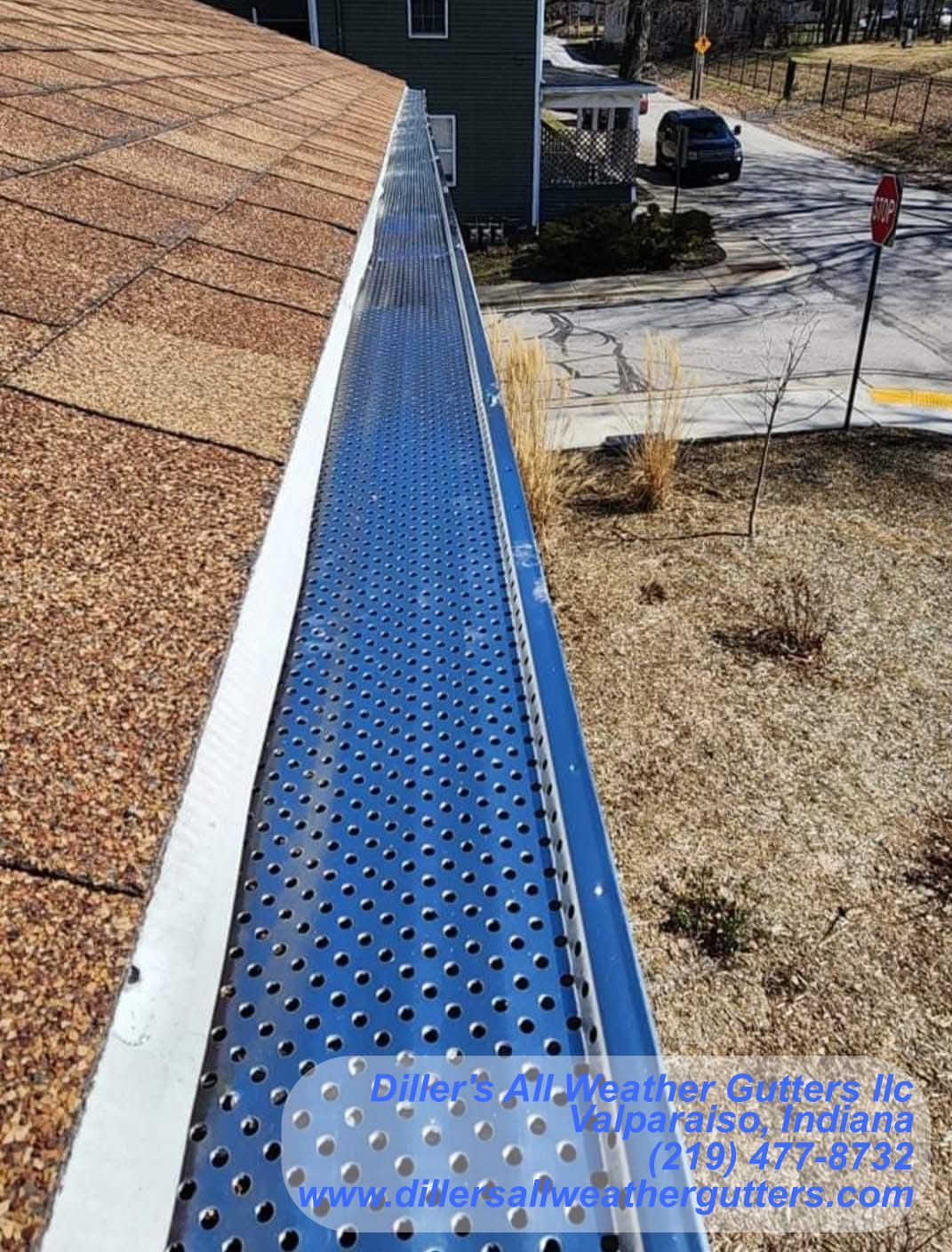 A blue gutter with holes in it is on the side of a house. Gutter installation in Northwestern Indiana
